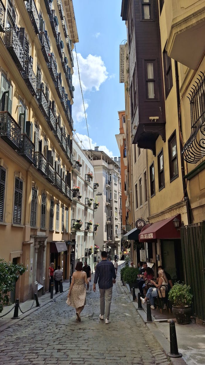 A picturesque European street with two people walking under a clear day sky. Vibrant urban life.